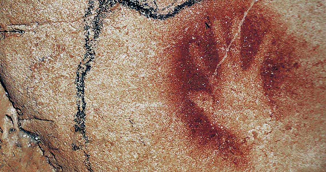hand outlined by ochre dust on cave wall